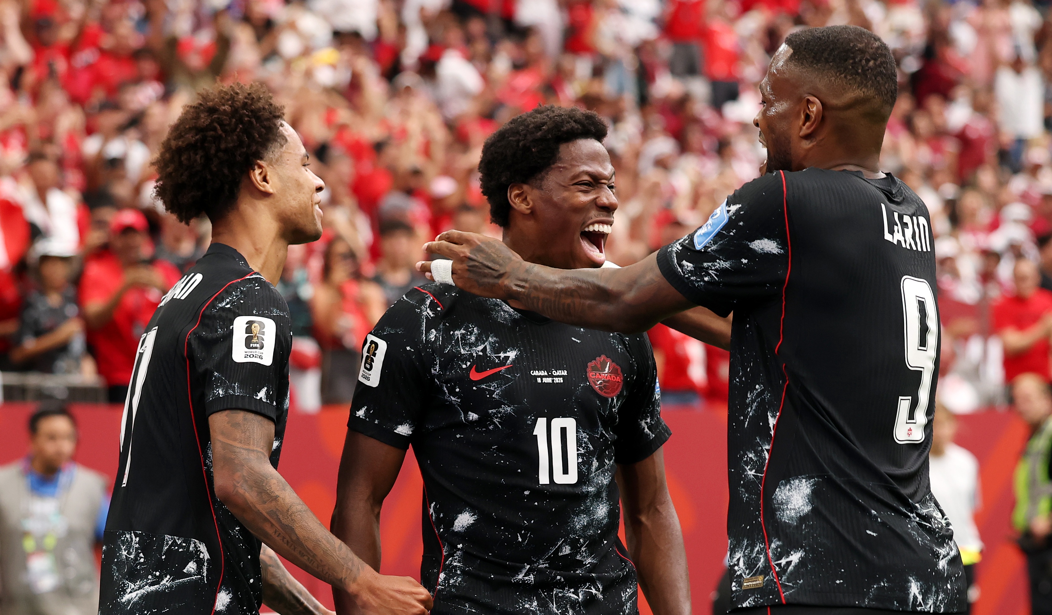Jonathan David of Canada celebrates with Tajon Buchanan and Cyle Larin after scoring his team's second goal during the FIFA World Cup 2026 Group B match against Qatar at BC Place Vancouver